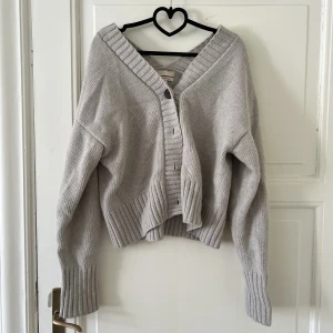 Oversized kofta från H&M  - En stickad kofta i mjuk ull- och kashmirblandning med boxig passform. Koftan har lång ärm med nedhasad axel och bakåtvriden axelsöm. V-ringning fram och bak, knäppning fram samt ribbstickad mudd vid ärmslut och i nederkant.  Fint skick använd fåtal gånger