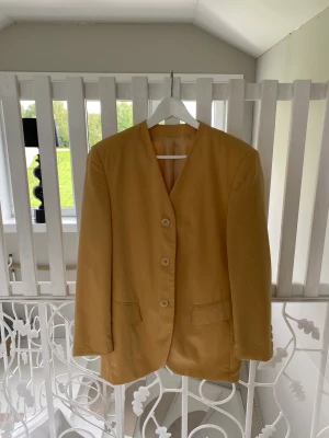 Kavaj - En otroligt fin gul kavaj som tyvärr aldrig kommer till användning hos mig.  Knappar som detaljer på ärmarna Axelvaddar  Går att knäppa ihop fram till.  Strl 40, aningen oversize på mig som vanligtvis har M. Går ner lite under rumpan på mig som är 170cm.