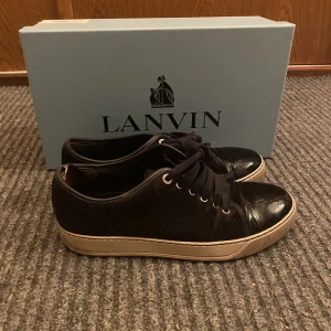 Lanvin skor - Säljer ett par väldigt snygga mörkblåa lanvin skor. De är relativt slitna men de är mest slitna inuti lite och lite solblekda utanpå. Köparen får med en lanvin box samt två små lanvin påsar en för vardera sko👍! (Pris kan diskuteras)