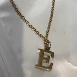 Guldhalsband  med bokstaven E - HELT NY!! Guld halsband i rostfritt stål som gör att den inte kommer bli röd! I bokstaven E!