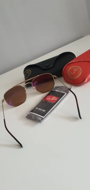 Solglasögon(ray ban) - Super fina äkta Ray ban solglasögon. Solglasögon kommer i original fodral + en extra originellt fodral i röd färg. Som ni kan se på bilderna är den röda fodralet lite sliten på kanterna men förutom det är allt annat i bra skick.  
