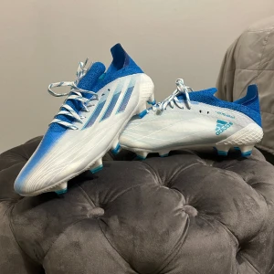 Adidas X  - Vit/blåa Adidas X fotbollsskor i storlek 41 1/3. Helt oanvända och kan användas till Fg/Ag.