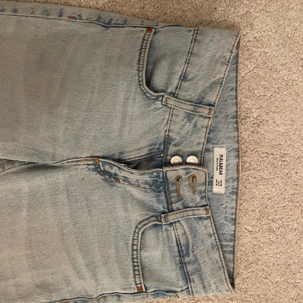 Lågmidjade bootcut/flare ljusblåa jeans från PULL & BEAR som inte finns att köpa längre. As snygga knappar och fina byxor, inga skador.Stl 32, skriv för fler bilder/ mått❤️. Jeans & Byxor.