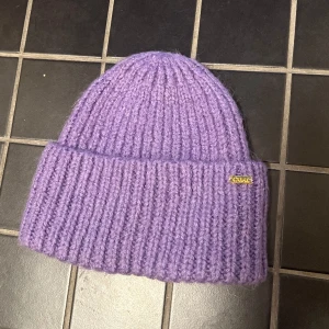 Lila mössa Carin Wester - Lila mössa från Carin Wester. Köpt förra året. Samma modell som årets men med gulddetalj istället för silver. 