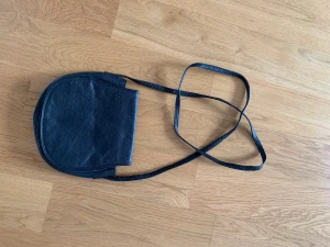 Vintage skinnväska  - Svart vintage skinnväska med blommig insida. Crossbody bag.  Ett litet fack med dragkedja i väskan.
