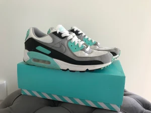 Nike air max 90 - Jag säljer ett par Nike air max som är vita, lite gråa, svart och ljus blåa. Dom är i jättebra skick samt lådan också. Dom är helt fel fria  medans sulan har väldigt lite skit på men det går bort.  Köpta för 1400kr. Priset kan diskuteras vid snabb affär. 