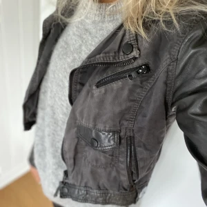 Skinnjacka dam - Häftig Svart skinnjacka i både skinn och tyg från märket Tigha i storlek S. 