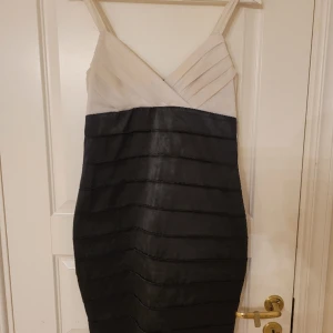 Svart-vit cocktailklänning  - Svart-vit cocktailklänning, som har använts ett par gånger på fester. Sitter jättebra och framhäver figuren vackert. Silkig material. 