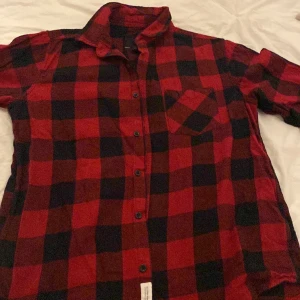 Flanellskjorta  - En röd och svart rutig skjorta i ett skönt matrial som passar till Julen