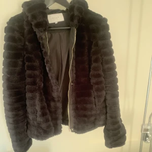Pälsjacka  - En svart riktigt gosig och mjuk pälsjacka från VILA 🩷Jackan är knappt använd så den är i nyskick! En stor luva, fickor, dragkedja och knappar ✨