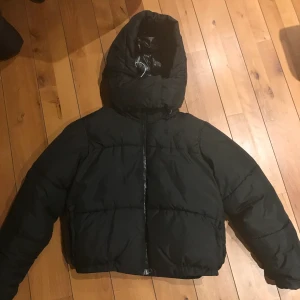 Svart pufferjacka - Säljer min gamla vinterjacka från weekday. Har en avtagbar luva, två fickor, man kan knäppa luvan/spännande den så hela halsen/hakan värms eller va man ska säga. Skickar såklart fler bild om ni undrar något❤️nypris=750kr, endast använd 1 vinter