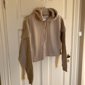 Croppad hoodie från Weekday  - Säljer denna snygga hoodie från Weekday. I fint skick. Storlek S. Croppad. Fickor på ärmarna. 