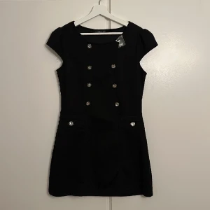 Klänning  - Kortklänning med knappar jättefin till både vardag och fest. Oanvänd 