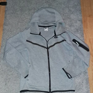 Nike tech fleece grey - Orsaken till att jag säljer denna tröja är att jag inte får använding för den. Tröjan är använd 2 gånger, fint skick. Nypris 1400 kr. Jag är 179cm på denna bild