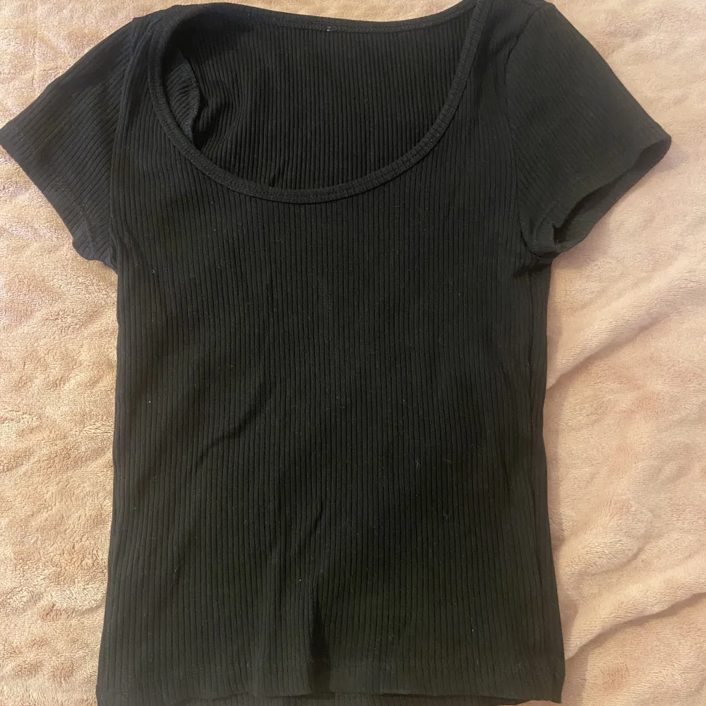 Svart ribbad t-shirt från H&M. Köpt för längesen men skicket är fint! Inga defekter på tröjan. Sitter som xs-s. Sista bilden är hur den sitter på fast i en annan färg.. Toppar.