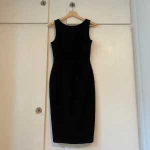 Svart klänning - Svart klänning i knälängd med låg v-rygg. 