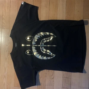 Bape T-shirt - Snygg svart bape tisha med guldigt sharktryck, använd 1-2 gånger, storlek M men sitter ganska litet, funkar som S. 