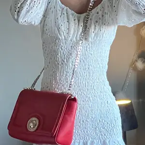 Säljer denna fina röda väskan från Versace som passar till vardag eller fest. Den har tyvärr fått en liten repa på framsidans ”detalj” därav priset❤️ Skriv för frågor eller fler bilder! 