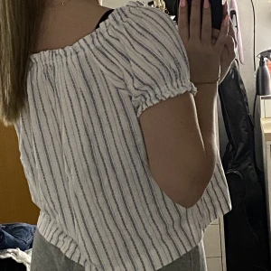 Randig tshirt - Supersöt, randig T-shirt med armar man kan ha uppe som en traditionell T-shirt eller ta ner så de blir off-shoulder. Resår upptill med löst o bekvämt tyg nertill. Super skön och fin till sommaren. 