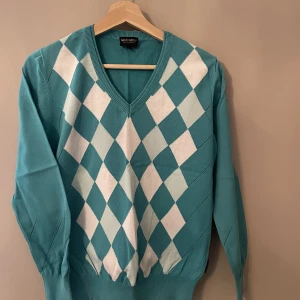 Tröja Galvin Green  - Snygg stickad tröja från Galvin Green. Stl S. Snyggt rutmönster och hålmönstrat vid ärmslut. 
