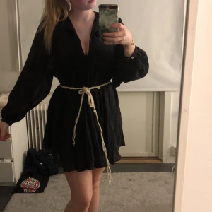 Söt klänning  - Super fin svart luftig klänning med en under kjol säljs då jag aldrig haft användning för den, gulligt borttagbart skärp med snäckor, finns en knapp upptill som går att stänga 