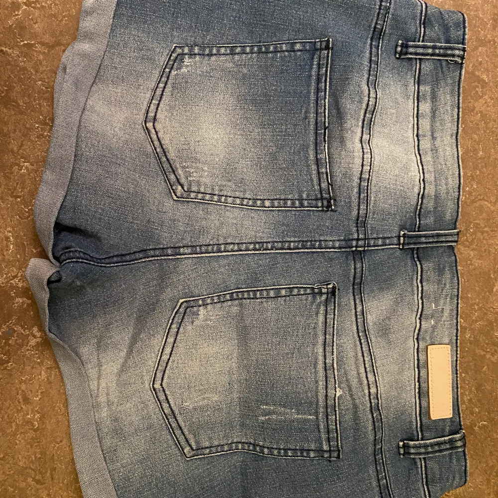 Ett par blåa jeansshorts med slitningar samt detalj på ena benet. Knappt använda. Köparen står för frakten. . Shorts.