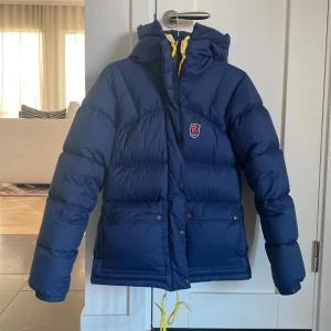 Fjällräven jacka, dam - Det här är en fjällräven jacka i färgen mörkblå. Modellen är ”Expedition Down Lite”. Den är i storlek xs. Jackan har använts under en vinter och är i nyskick. Nypris i butik är 6999 kr. Inga defekter. 