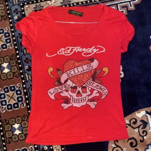 Röd ed Hardy tröja med rhinestones  - Röd ed Hardy tröja med rhinestones. Knappt använd i måttligt bra skick men saknar ungefär 3 rhinestones och lappen i nacken sitter löst(från vad jag hittar online verkar den ej vara äkta). Passar storlek S/M/L💗