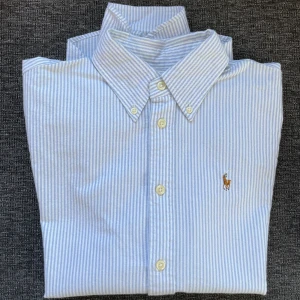 Ralph Lauren skjorta stl. XS  - Blå och vit randig RL skjorta i fint skick. Använd ett fåtal gånger. Säljer den pga för liten. Tycker den är såå snygg till ett par jeans!  Den är 100% bomull och extra knappar medföljer.  Frakt tillkommer. 