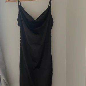 Svart satinkläning  - Superfin ”satin”klänning.  Inga speciella detaljer förutom att den går ner lite vid bröstet 