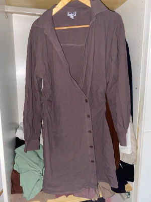Brun Skjort klänning - En snygg asymmetrisk skjortklänning i brun. Aldrig använd köptes för 400kr