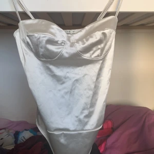 Satinbody - Satinbody från NLYONE. Med reglerbara axelband och tre knappar i grenen. Passar perfekt till våren och sommarens alla fester och tillställningar.  Har även en till likadan fast i svart i storlek S!🖤🤍