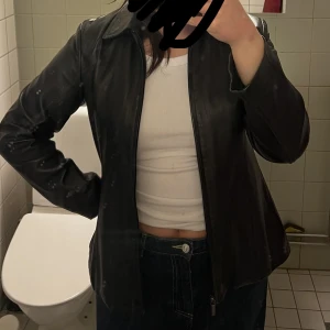 Läderjacka - Svart läderjacka (90% säker det är äkta läder) säljes. Superfint skick, endast en liten prick på kragen som knappt syns. Därav det billiga priset. Strl: S/M eller one size beroende på hur man vill att den sitter. ❤️‍🔥