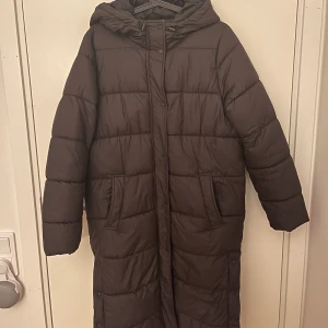 Brun lång dunjacka - Brun dunjacka från only, köpt förra året och använt några gånger förra vinter. En väldigt snygg och varm jacka, med en liten oversized look. Jag är 172 och den går till mina vader, funkar perfekt nu i snön! Köpt för 800 och i fint skick.
