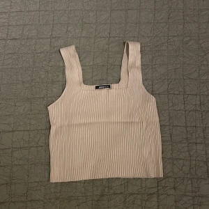 Croppat linne från Gina Tricot - Ett ribbat beiget linne från Gina Tricot. Mycket strech. Endast använt en gång. Superfint till vardags eller fest året om.  