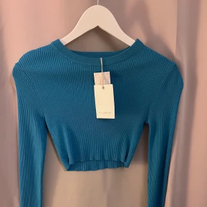 Blå ribbad kortare tröja  - Det är en väldigt blå tröja från PULL&BEAR. Den är ribbad och har en liten slit vi slutet av ärmen. Kort också! Oanvänd. 