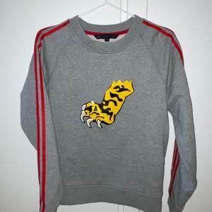 Marc Jacobs sweatshirt in gray with res stripes on the arms and a tiger claw as motive. You can still buy it at Farfetch for 300 euro. Used only once. Size S and true to size. Shipping within Sweden is included in the prize.