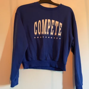 En blå sweatshirt med tryck. - En blå sweatshirt med ett vit tryck. Använd Storlek:M