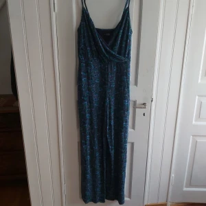 Jumpsuit i blåblommigt mönster - Lång jumpsuit med vida byxben, smala axelband med justering och urringning i mjukt material med blåblommigt mönster