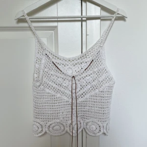 Virkad vit topp - En jättefin virkad sommartopp med snören! Snörena går att ta bort och har pärlor/fjädrar på sig. Den är köpt vintage och passar en S! 💘