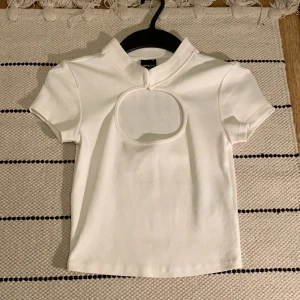 Vit top med utskuren detalj - Vit top i storlek XS, från Ginatricot. Skönt material, tajt passform. Har ej använt den!