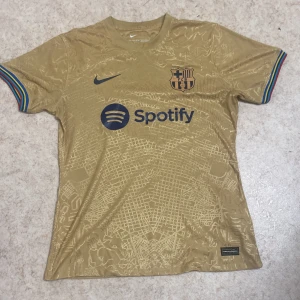 Barcalona t shirt (guld) - Barcelona t-shirt i storlek M som knappt är använd därav priset. Tröjan är hel äkta och köptes in för 700kr.