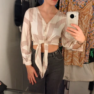Söt blus - Blusen är beige med små röda detaljer. Storleken är EUR 36 och den passar bra. Den är lite genomskinlig då materialet är tunnt men det är ett gulligt plagg.
