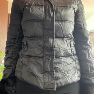 Svart din jacka med päls på armarna - Svart dunjacka från ”Angelo Mariani”. Päls vid handlederna som man kan se på bilden. Bra skick, men lite skrynklig.