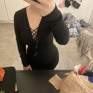 Svart klänning - Svart klänning med snörning framtill, går till lite över knäna. Från Gina 