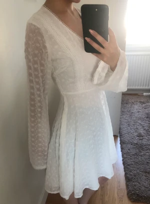 Vit klänning  - Vit klänning med broderingsdetaljer och vida armar.  Storlek: 32  Märke: NA-KD Använd 1 gång, nyskick 