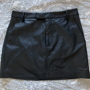 Läderkjol  - Kjol i läder. Fint skick, knappt använd. Ca 70 cm i midjan. Rymliga fickor fram.