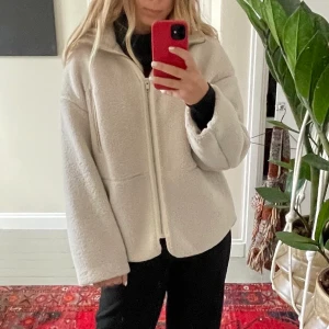Höst/vårjacka - Ullig jacka från H&M. (Inte äkta ull) Bra skick och lagom varm för höst/vår men har även haft den på vintern med en tjocktröja under. Nyansen är vit med lite beigt inslag.  