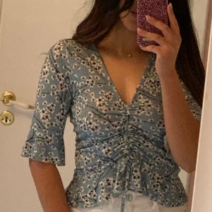 Blus - Blommig blus med dragsko på magen från gina tricot i storlek XS. Är i väldigt bra skick inga defekter.  Mötas i Stockholm eller fraktar. Köpare står i frakt.💕