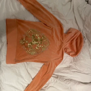 Juicy couture tröja - Säljer en skitsnygg zip up hoodie från juicy couture. Det är deras gamla modell💕Färgen är lite ljusare och mer aprikos i verkligheten (Tredje bilden) och den är i storlek S. 